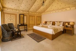 a bedroom with a bed and a chair at The Saffron Desert Camp, Jaisalmer in Jaisalmer