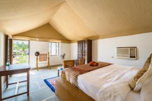 a bedroom with a large bed and a desk at The Saffron Desert Camp, Jaisalmer in Jaisalmer
