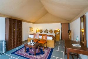 a hotel room with a bed and a desk and a table at The Saffron Desert Camp, Jaisalmer in Jaisalmer