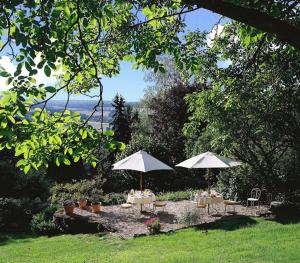 twee tafels en stoelen met parasols in een tuin bij Clos de Fougères - Cocon in Montoillot