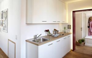 a kitchen with white cabinets and a sink at KönigsSCHLAF No5 - Barrierefrei, chic & gemütlich in der Altstadt in Konstanz +10 photos