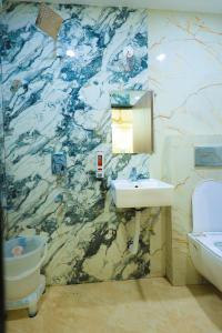 a bathroom with a marble wall with a sink and a toilet at Maa Kela Devi Shanti Atithi Bhawan in Vrindāvan