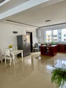 a kitchen with a table and a stainless steel refrigerator at Hakuna Matata Ocean View Home - Msasani Near Masaki in Dar es Salaam