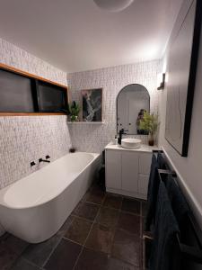 a bathroom with a tub and a sink and a mirror at Ocean Views - Ocean Grove, Spectacular Family Home in sought after Location in Ocean Grove