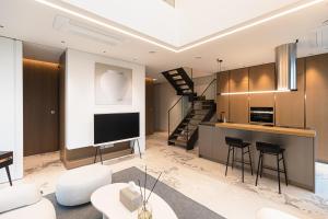 a living room with a tv and a kitchen and a staircase at Caelum Black Gangnam Luxury Residence in Seoul