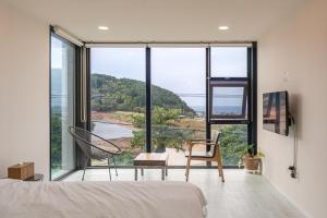 a bedroom with a large window with a chair at Trip Recipe in Jeju +82 photos