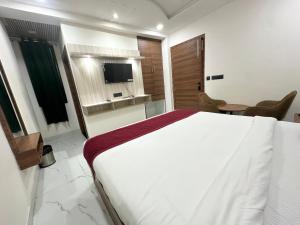 a bedroom with a large white bed and a television at Hotel Dev Vilas , Agra in Agra