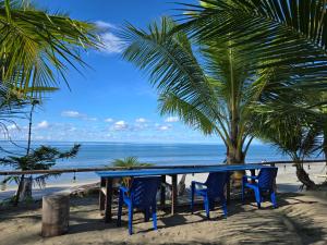 a table and chairs on the beach with a palm tree at Amban Beach House in Manokwari