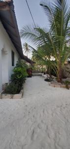 a patio with palm trees and a white building at Nionje Garden Villa in Jambiani