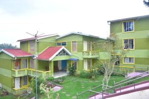 a green and yellow house with a yard at Mookambigai Residency in Kodaikānāl