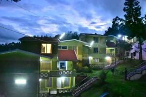 a house with lights on in the yard at night at Mookambigai Residency in Kodaikānāl