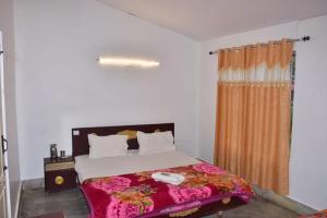 a bedroom with a bed and a window with a bedspread at Mookambigai Residency in Kodaikānāl