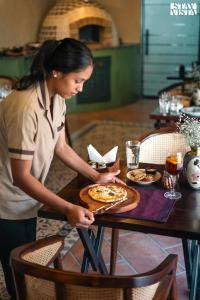 a woman preparing a pizza on a table at StayVista at The Harbhson House with Pool, Jacuzzi, Sauna room, Woodfire Pizza, Projector in Bidauli