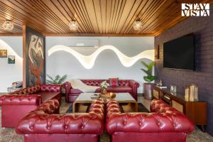 a living room with red leather couches and a tv at StayVista at The Harbhson House with Pool, Jacuzzi, Sauna room, Woodfire Pizza, Projector in Bidauli