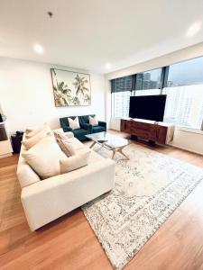 Una sala de estar con un sofá blanco y un televisor de pantalla plana. en Ocean View Spa Apartment in Q Tower, en Gold Coast