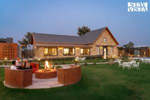 two people sitting in front of a house at StayVista at The Harbhson House with Pool, Jacuzzi, Sauna room, Woodfire Pizza, Projector in Bidauli