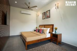 a bedroom with a bed and a ceiling fan at StayVista at The Harbhson House with Pool, Jacuzzi, Sauna room, Woodfire Pizza, Projector in Bidauli +28 photos