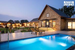 a swimming pool in front of a house at StayVista at The Harbhson House with Pool, Jacuzzi, Sauna room, Woodfire Pizza, Projector in Bidauli