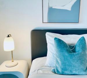 una almohada azul sentada en una cama junto a una lámpara en Ocean View Spa Apartment in Q Tower, en Gold Coast