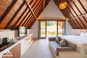 ein Schlafzimmer in einer Villa mit einem Bett und einem Sofa in der Unterkunft Kanaka Cottage by Bukit Vista in Uluwatu
