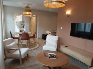 a living room with a tv and a table and chairs at Bel appartement en centre-ville de Cambrai in Cambrai