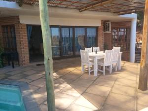 une table blanche et des chaises sur une terrasse dans l'établissement Sunset Cottage - Own Water - Own Electricity, à Pretoria