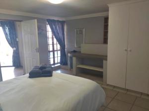 une chambre avec un lit blanc avec des serviettes dessus dans l'établissement Sunset Cottage - Own Water - Own Electricity, à Pretoria