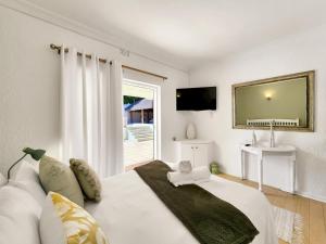a bedroom with a large white bed and a television at 70 on Brander in Cape Town