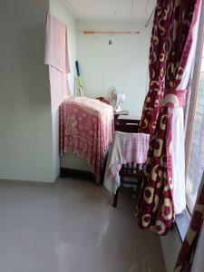 Zimmer mit einem Tisch, einem Tisch und einem Fenster in der Unterkunft 1 big furnished studio apartment with a pantry including fridge, utensils, gas stove and a washing machine with attached bathroom that can accommodate minimum 4 people in Igatpuri