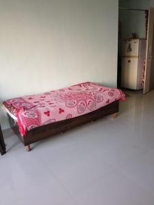 ein Bett in einem Zimmer mit einer rosa Decke darauf in der Unterkunft 1 big furnished studio apartment with a pantry including fridge, utensils, gas stove and a washing machine with attached bathroom that can accommodate minimum 4 people in Igatpuri