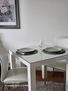 a white table with two plates and a wine glass at Valjevo 13 Apartman in Valjevo