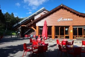 a restaurant with tables and chairs and a red umbrella at Planta baja con jardín y piscina en Olopte in Olopte