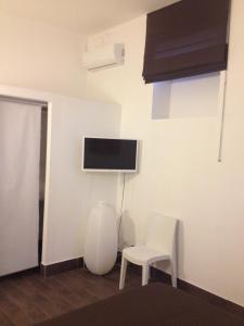 シラクーサにあるGlobe Trotter Apartmentの白い椅子2脚と壁掛けテレビが備わる客室です。
