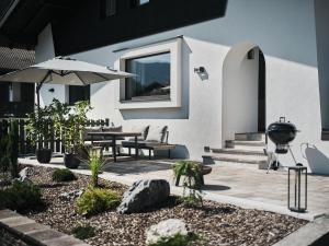 a patio with a grill and a table with an umbrella at Lodge am Wetterstein in Ehrwald