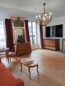a living room with a table and a chandelier at Le Royal in Bayeux