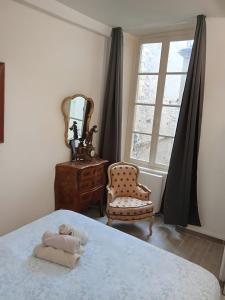 a bedroom with a bed and a chair and a mirror at Le Royal in Bayeux