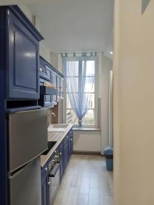 a kitchen with blue cabinets and a sink and a window at Le Royal in Bayeux