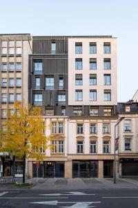 a tall building with a tree in front of it at The Central City - Luxury Serviced Residence in Luxembourg