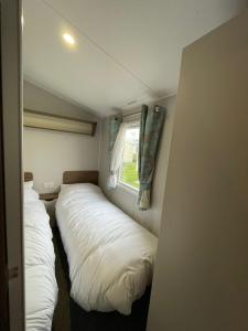 zwei Betten in einem kleinen Zimmer mit Fenster in der Unterkunft 3 Bed Presthaven in Talacre