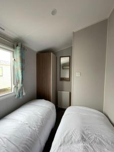 zwei Betten in einem kleinen Zimmer mit Fenster in der Unterkunft 3 Bed Presthaven in Talacre