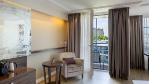 a hotel room with a chair and a table and a window at Pullman Munich in Munich