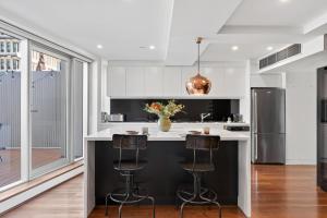 シドニーにあるSplit Level City Loft with Private Balconyの黒い島(バースツール付)のあるキッチン