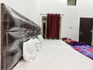 NaimishāranyaMa vindhyavasini Atithi Bhavan的一间有一张床的房间，墙上挂着一幅画 更多4张照片