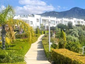 a pathway through a garden with a white building at Modern Poolside Apartment in Sun Valley in Ayios Yeoryios