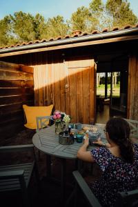 a woman sitting at a table on a patio at La Fournière de Jean - La Téouleyre in Saint-Julien-en-Born