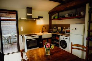 a kitchen with a wooden table with flowers on it at La Fournière de Jean - La Téouleyre in Saint-Julien-en-Born