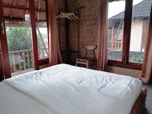 a bedroom with a bed and a balcony with windows at D'Tebe House Kelating in Tabanan