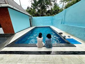 two girls sitting next to a swimming pool at Cloud Lacasa in Athirappilly
