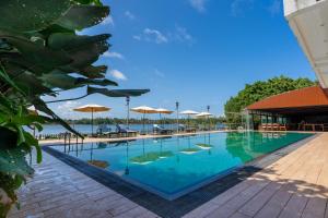 a large swimming pool with tables and umbrellas at Dutch Gate Bentota in Bentota