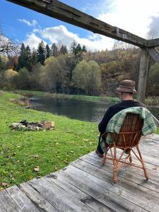 a man sitting in a chair on a wooden deck at Те Село in Velyka Volosyanka +6 photos